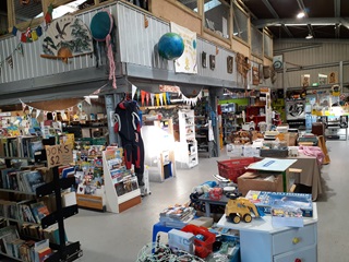 The inside of the Tip Shop showing stacks of books, toys and items hanging from the ceiling.