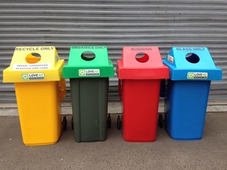 Four bins with hoods in four colours: yellow, green, red and blue.